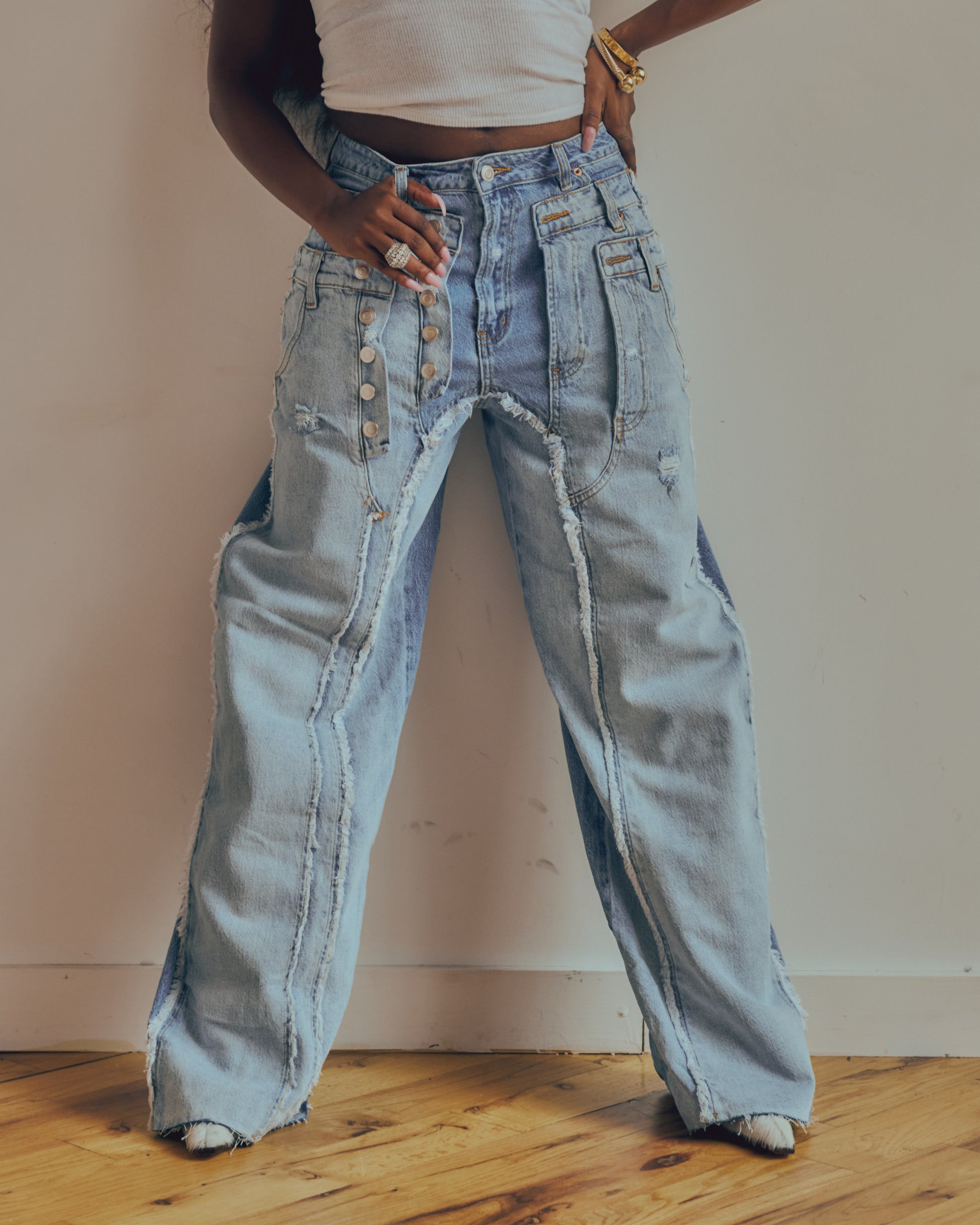 Person wearing light blue distressed jeans standing on a wooden floor.
