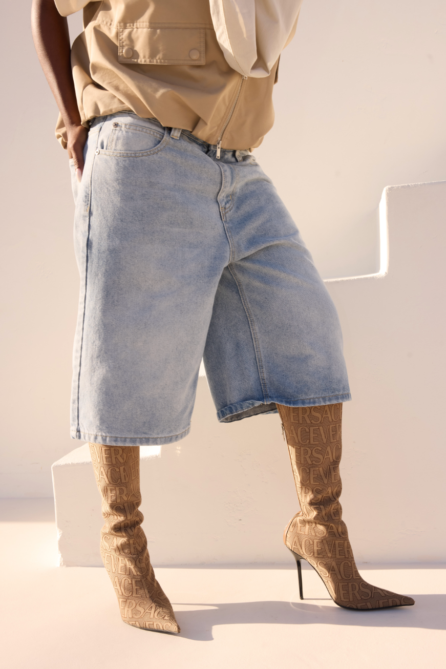 Person wearing light blue denim shorts and brown high-heeled boots against a white background