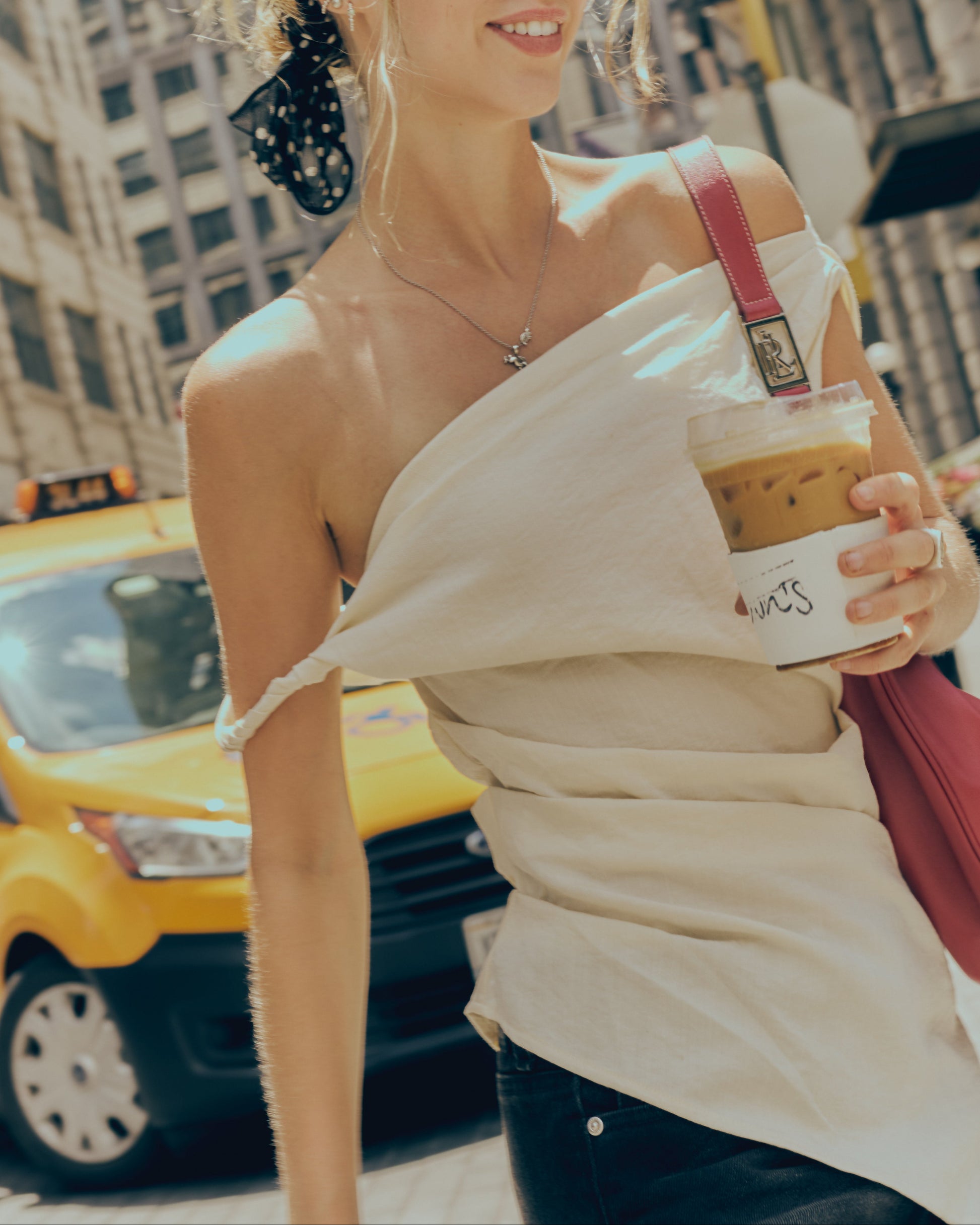 Woman holding a coffee cup with a yellow taxi in the background