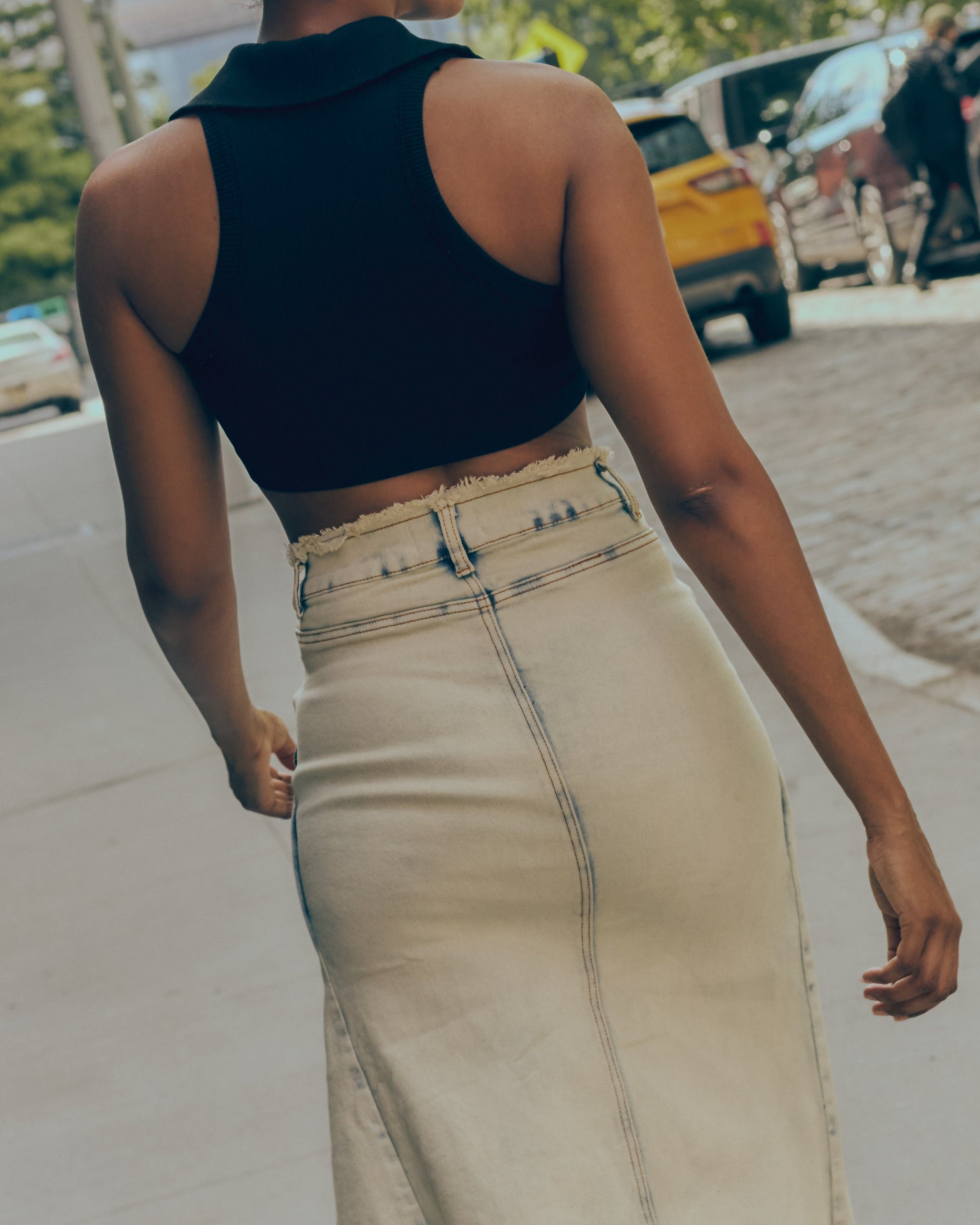Woman walking on a sidewalk with a cityscape in the background
