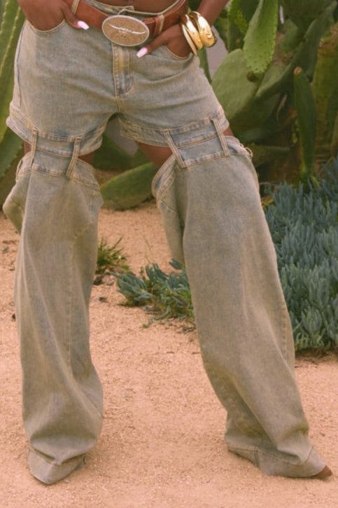 Person wearing a white tank top and light-colored pants standing in front of cacti.